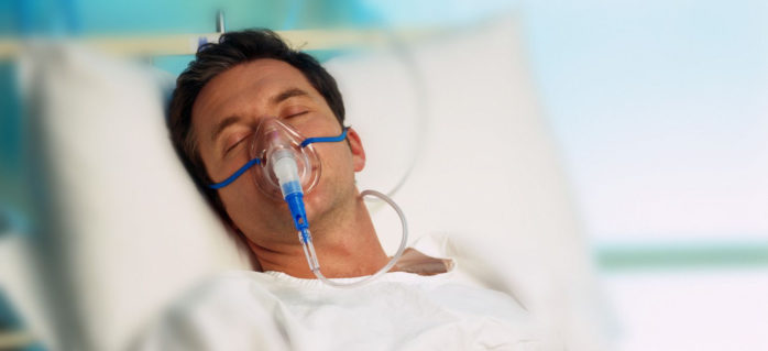 Portrait of a man with an oxygen mask in a hospital bed
